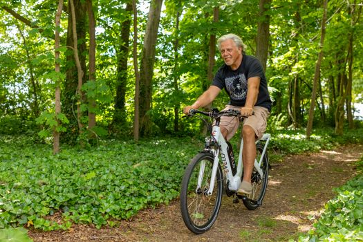 60 year old woman riding step-through eBike on paved city path
