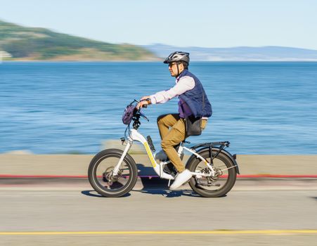 Adult rider commuting on a budget electric bike on a city street with traffic